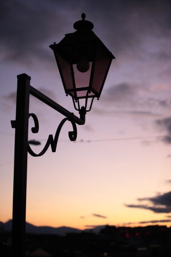 A vertical low angle shot of a street lamp captured during the sunset