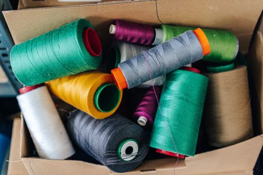 Detail close up photo of spools of threads. Spool thread in different colours. Bulk spools of threads for sewing.