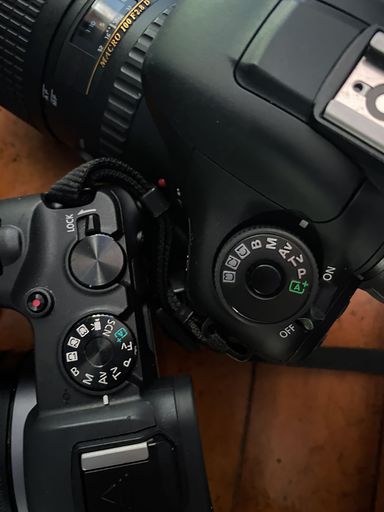 A vertical closeup shot of two professional DSLR digital cameras on a table