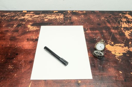 A beautiful shot of a black marker on a white paper with a vintage pocket watch