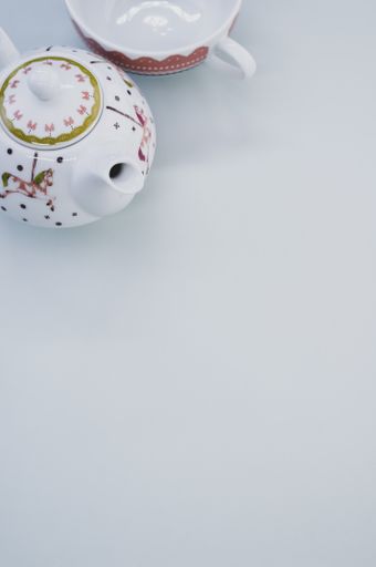 A vertical shot of decorative teapot with cup isolated on white background