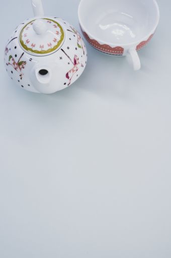 A vertical shot of teapot with cup isolated on white background