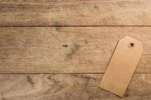A top view of cardboard tag with a hole on a wooden table with copy space
