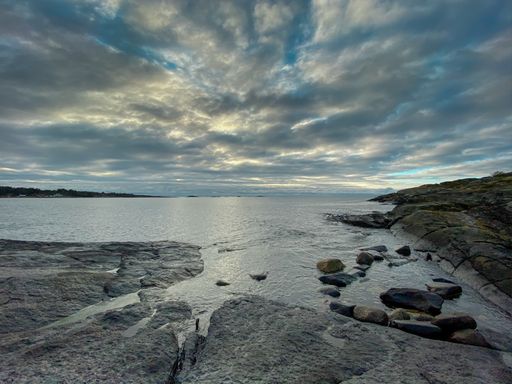 A rocky shore surrounded by the sea under a cloudy sky on a gloomy day