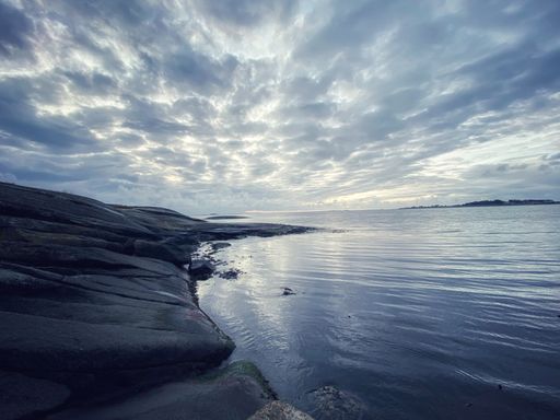 A rocky shore surrounded by the sea under a cloudy sky on a gloomy day