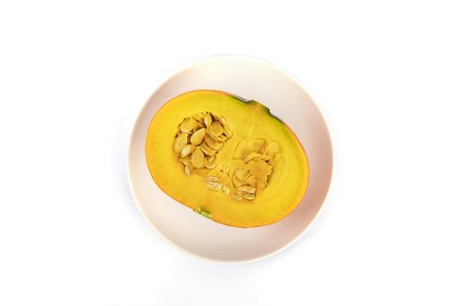 A top view of freshly sliced pumpkin on a pink plate isolated on a white background