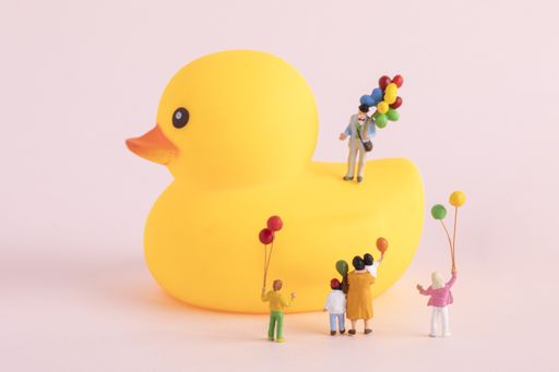 A closeup shot of cute figurines playing with balloons playing on a rubber duck