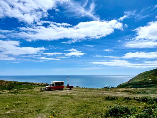 A red and white bray head coffee van on the green coats of the sea in Ireland under the blue sky