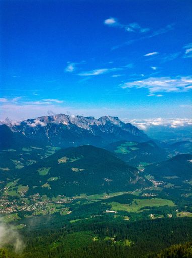 A vertical shot of a beautiful cloudy sky over a mountain range covered with lush summer vegetation