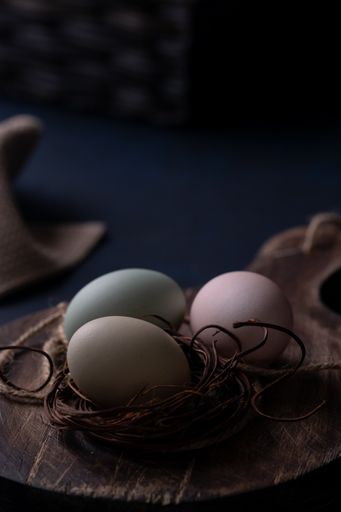A vertical shot of colorful farm eggs with rustic decorative ropes on a wooden board