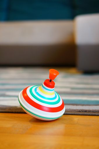 A vertical shot of colorful spinning top on wooden floor next to carpet
