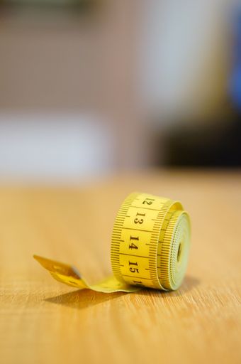 A vertical selective focus shot of yellow measuring tape on wooden table