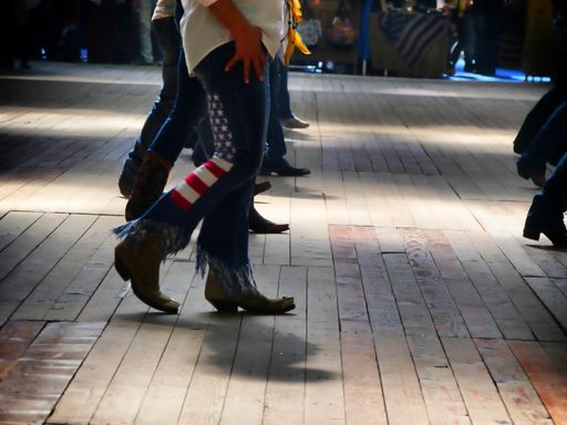 Traditional western folk music dancer's legs in cowboy boots dancing on a wooden old floor