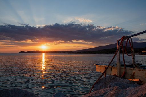 Seascape with sun reflection over large rocks and calm Aegean sea in Thasos island, Greece, beautiful orange skyline at sunset