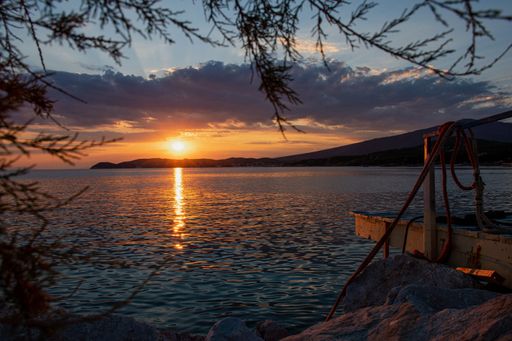 Seascape with sun reflection over large rocks and calm Aegean sea in Thasos island, Greece, beautiful orange skyline at sunset