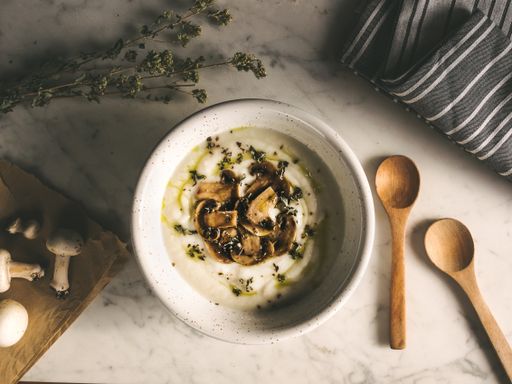 A top view of a bowl of mushroom soup on a kitchen table