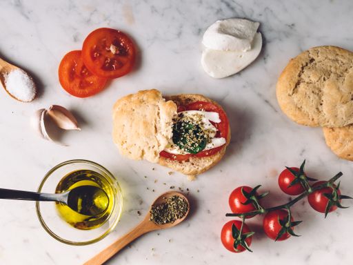 A top view closeup of the oil, bread, fresh cherry tomatoes, mozzarella, and spices