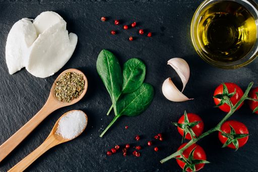 A top view closeup of the fresh cherry tomatoes, mozzarella, spice tablespoon, garlic, and spinach