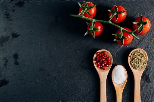 top view background of colorfull food ingredients :  fresh cherry tomatoes, spices tablespoons. healthy mediterranean  diet. Dark background
