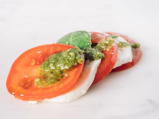 A closeup shot of Caprese salad with sliced fresh tomato, mozzarella and basil
