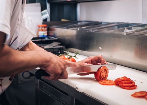 A chef preparing and cutting tomatoes in a professional kitchen