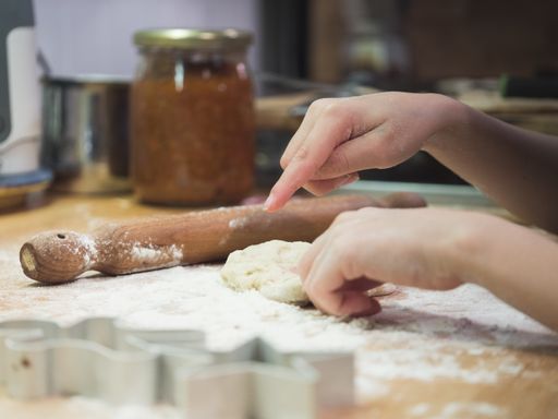 A closeup shot of a child making dough with rolling pin and cookies shapes