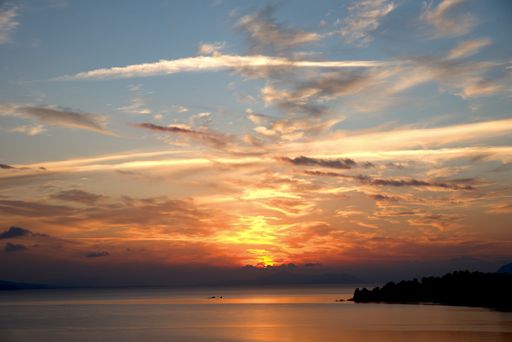 A majestic seascape view with a beautiful cloudy sky and setting dow sunset sun