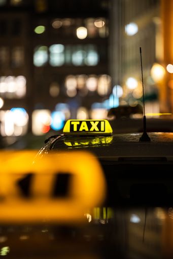 A vertical shot of the yellow TAXI signs on the taxis captured at night