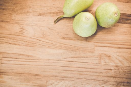 A top view of green pears on a natural wooden surface