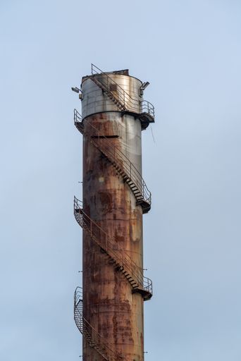 A vertical shot of a rusty steel chimney of an old factory