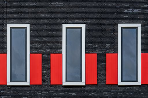 A fragment of a modern building brick facade with three windows in a row