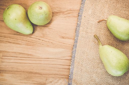 A top view of green pears on a natural wooden surface