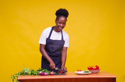 A closeup shot of a young African lady cooking wearing an apron