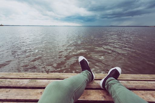 A man sitting on a wooden board in front of the lake