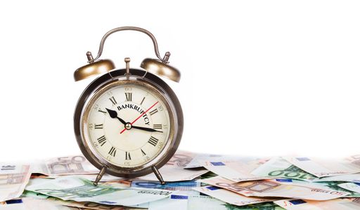 A bankruptcy alarm clock on banknotes isolated on white background, time is money concept