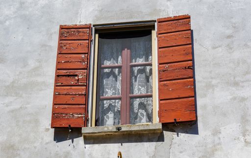 A shot of a window with old wooden covers on a sunny day