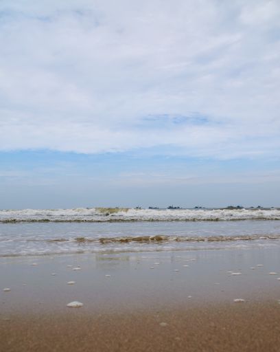 A vertical shot of waves washing a sandy coast