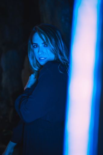 A vertical shot of an attractive young Caucasian woman illuminated by blue color