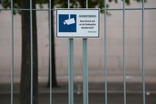 A closeup of a surveillance camera sign on a fence
