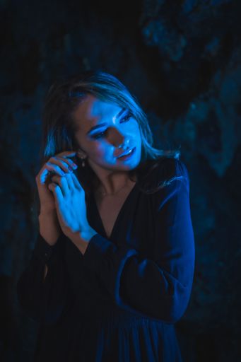 A vertical shot of an attractive young Caucasian woman illuminated by blue color