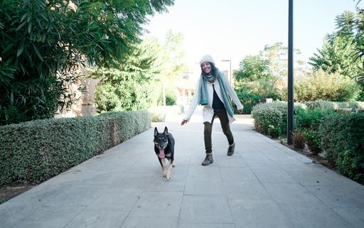 A young pretty woman in a white cap walking her dog and playing with him