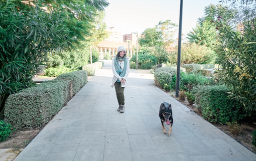 A young pretty woman in a white cap walking her dog and playing with him