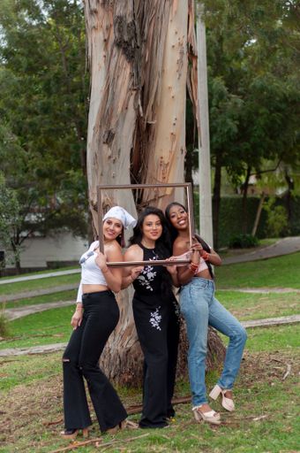 The three happy young friends posing with photo frame