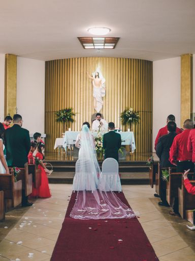 Young couple standing in front of altar at church on wedding day next to the paster and other people standing around them