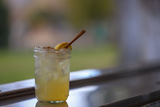 A summery cocktail in a glass jar with cinnamon garnish.