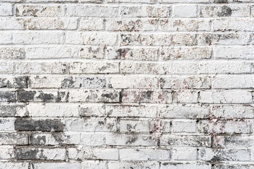 A plain brick wall background with spots of gray in the worn white paint