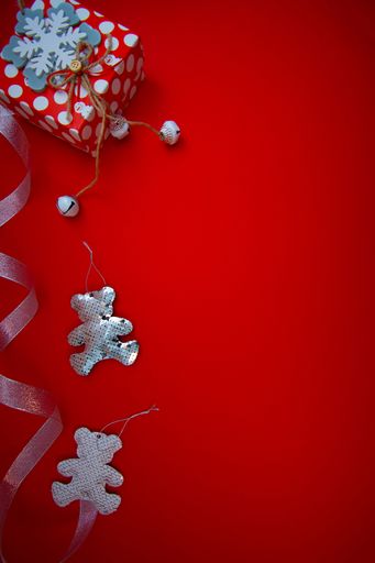 A vertical shot of a red gift box and Christmas ornaments with copy space isolated on red background