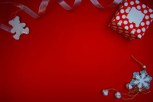 A top view of a red gift box and Christmas ornaments with copy space isolated on a red background