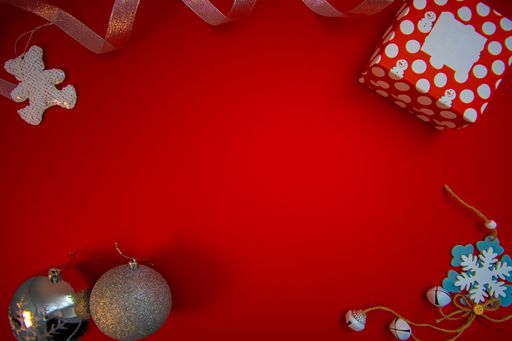 A top view of a red gift box and Christmas ornaments with copy space isolated on a red background