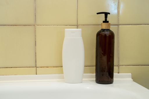 A closeup of shampoo and liquid soap dispenser  on a white bathroom sink